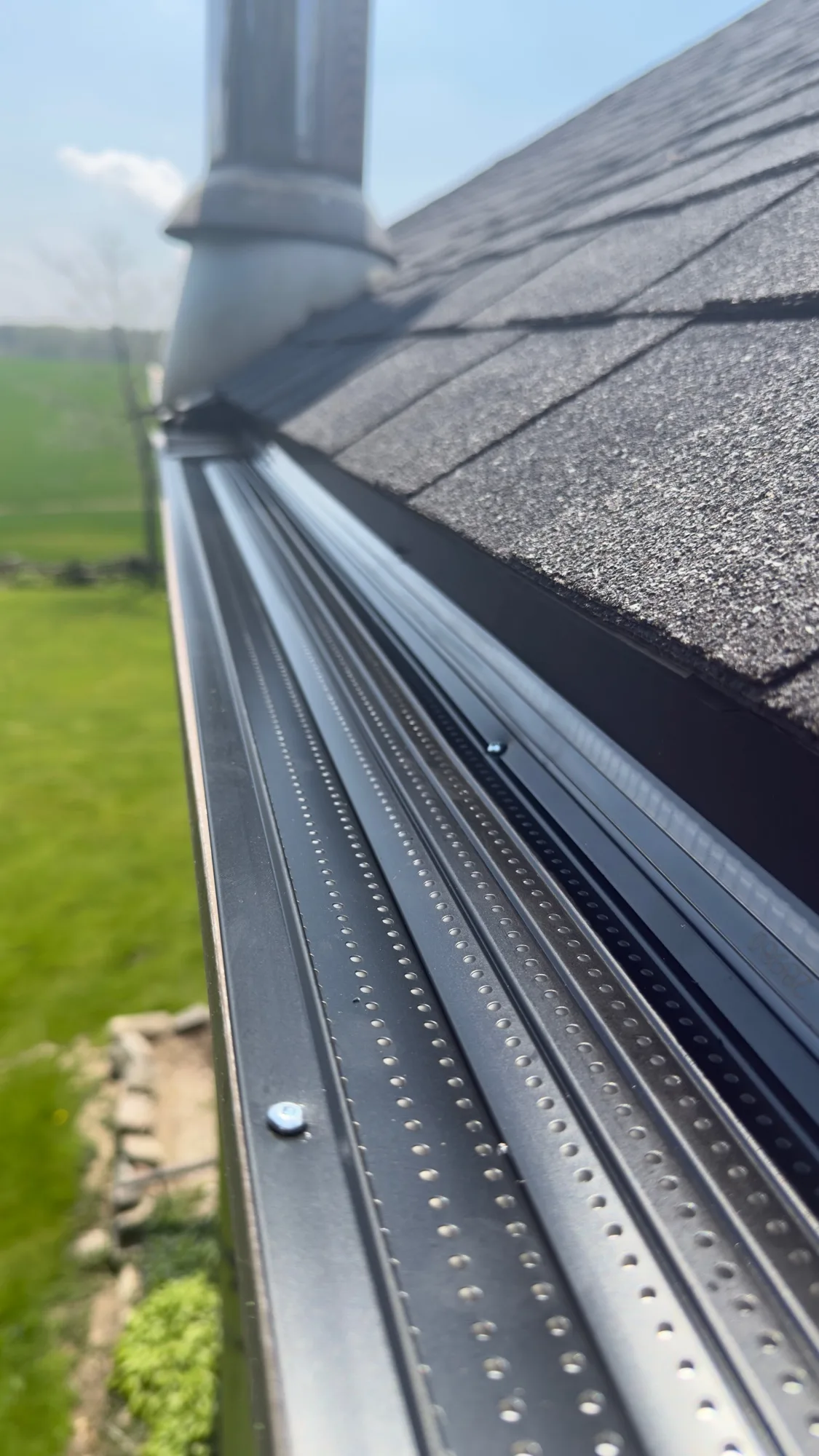 Close-up of black double-perforated gutter guard rail detail on rural home — D&D Home Services