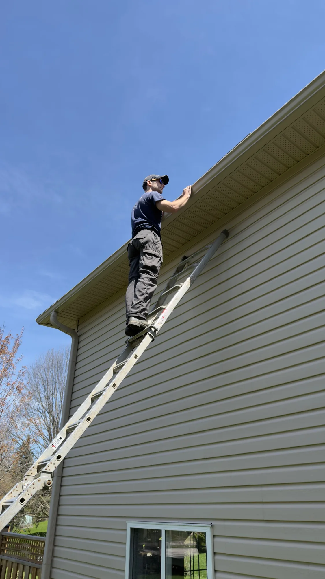D&D technician fitting gutter guard panel along eavestrough edge on residential home — K-W gutter guard install