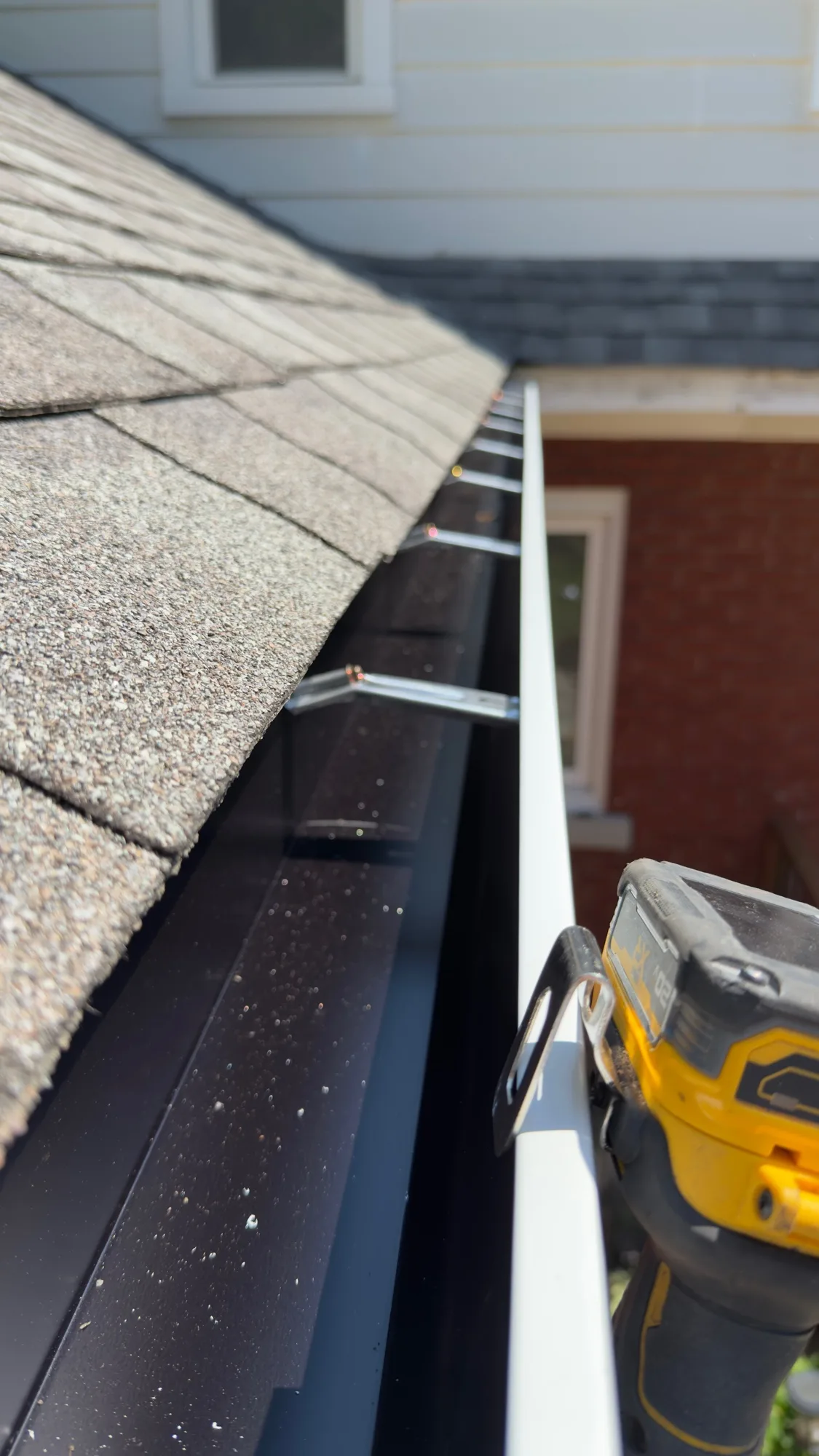 New eavestrough being installed with hidden hangers and DeWalt drill — D&D Home Services Kitchener-Waterloo