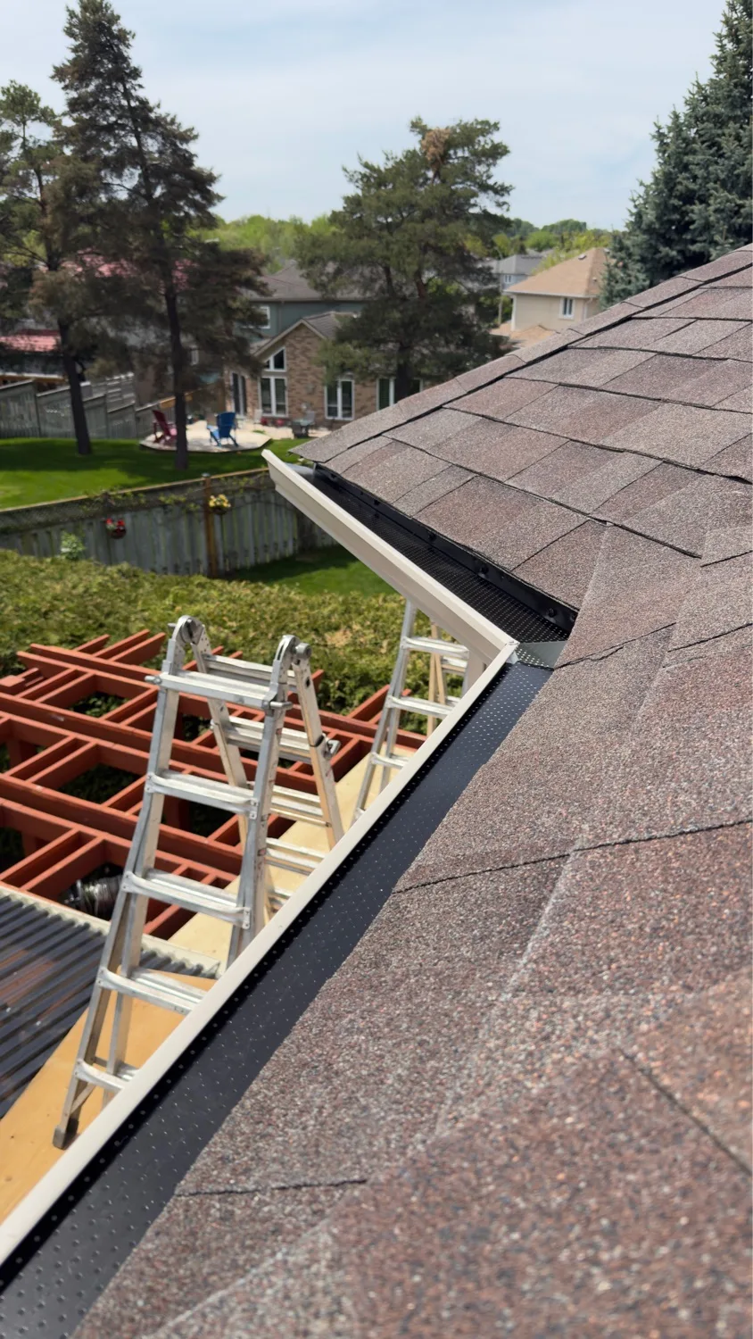 Black perforated gutter guard installed along asphalt-shingle roof edge — D&D Home Services Kitchener-Waterloo