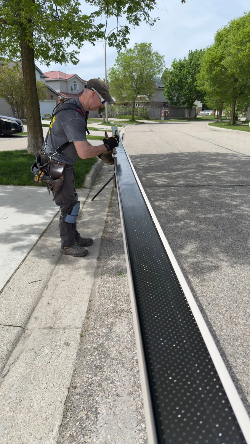 D&D Home Services technician fitting perforated gutter guard at ground level before roof install